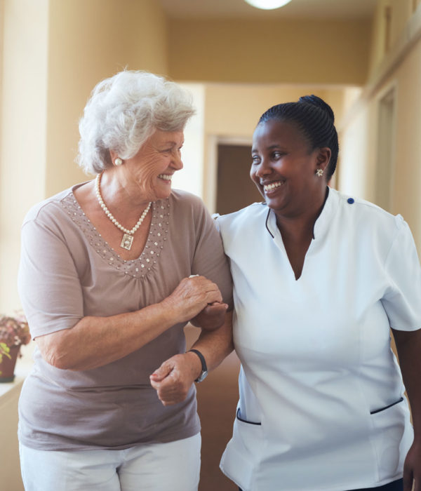 Senior lady and nurse walking down a hallway together