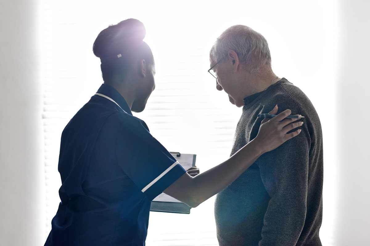 Home-aid looking over paper work with elderly man