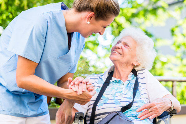 Lady wearing scrubs holding another woman's hands reassuringly