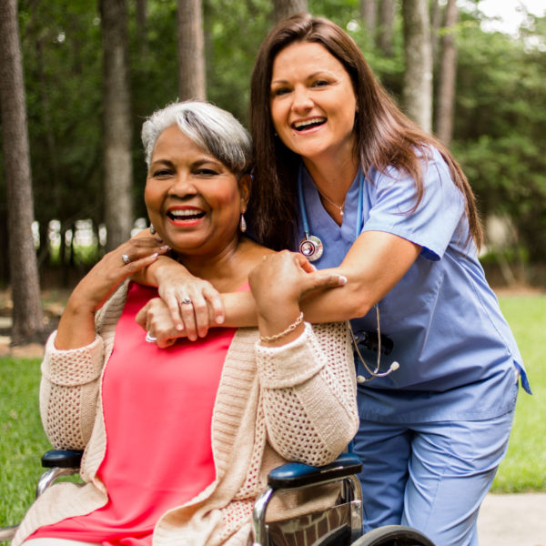 Nurse hugging lady in wheelchair