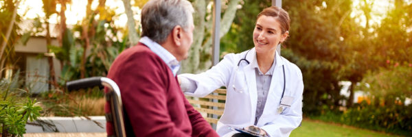 Doctor speaking and smiling to man in wheelchair