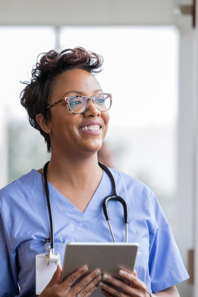 Beautiful nurse smiles while holding digital tablet